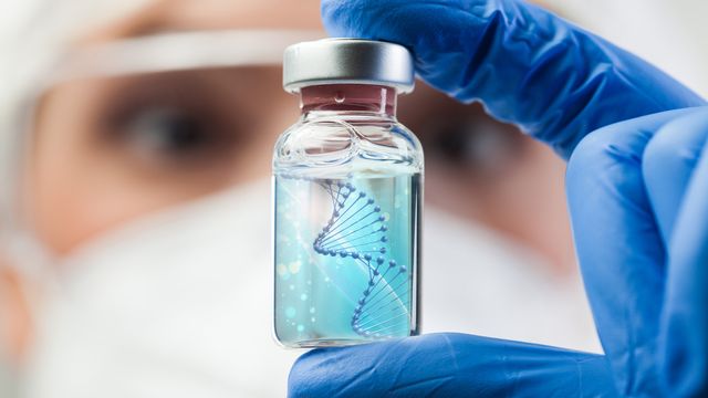 A researcher holding up a drug vial to the camera. A image of a DNA double helix is digitally-superimposed onto the blue liquid in the vial. 