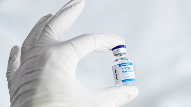 A vial of SARA-Cov2 mRNA vaccine held in a gloved hand 
