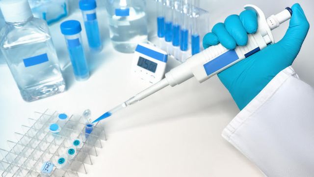 A blue-and-white scientific background showing an automatic pipette dispensing liquid samples. 